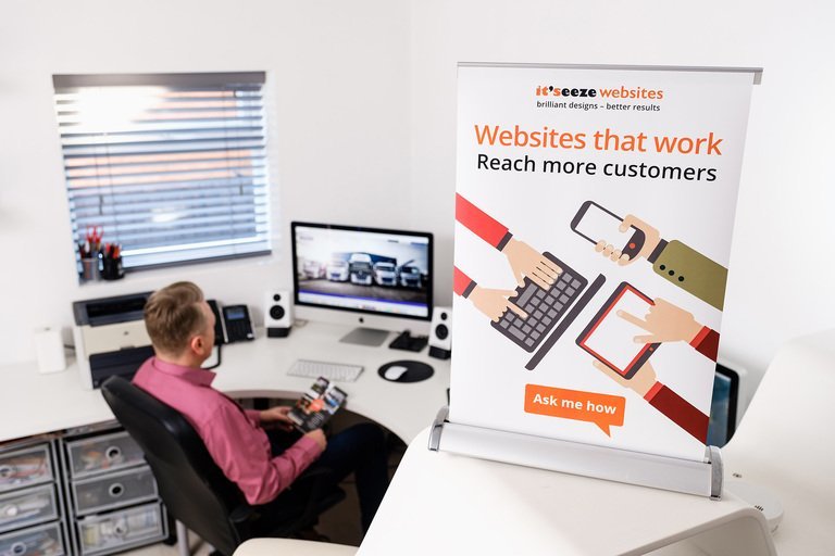 A man sat at his computer with a big banner showing an advert it'seeze websites